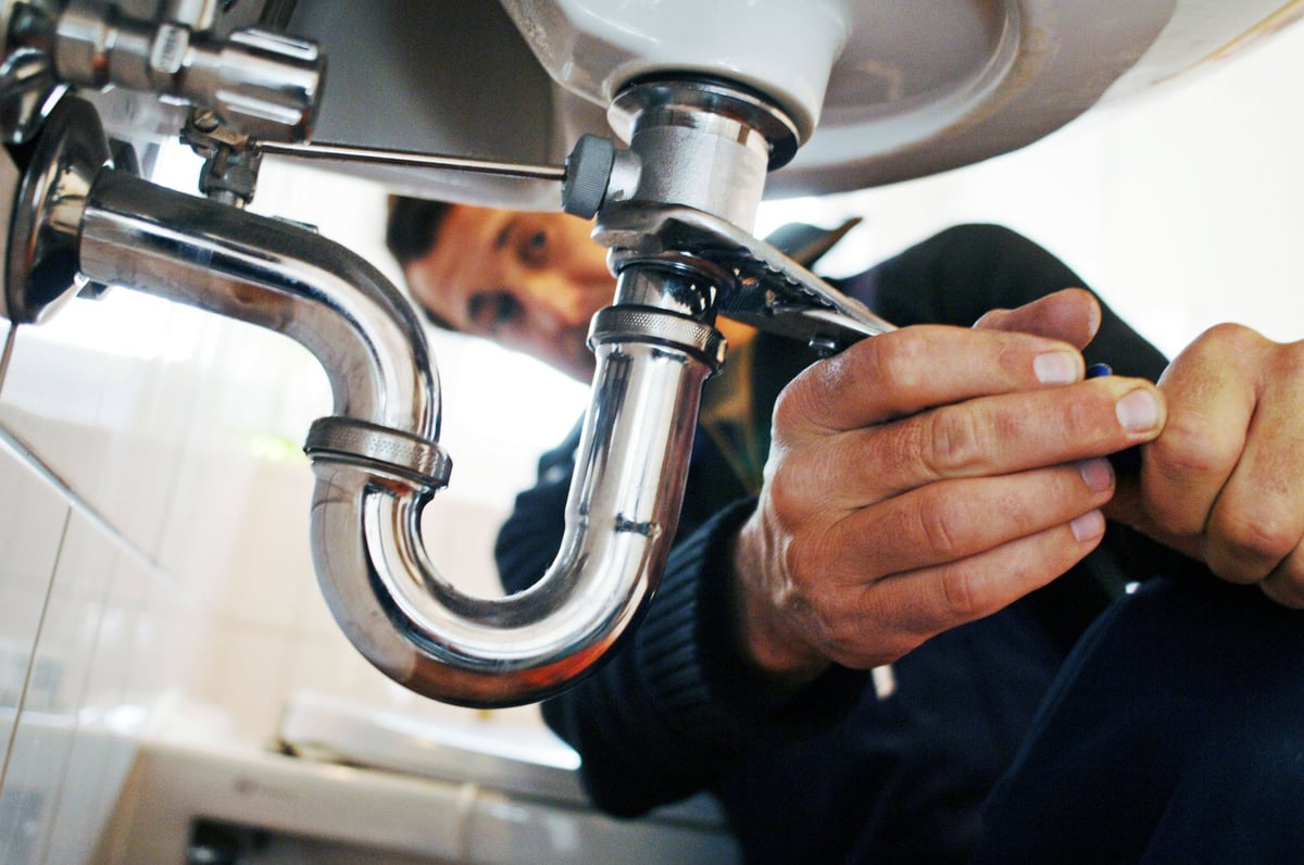 Plumber repairing a commercial sink and metallic fixture